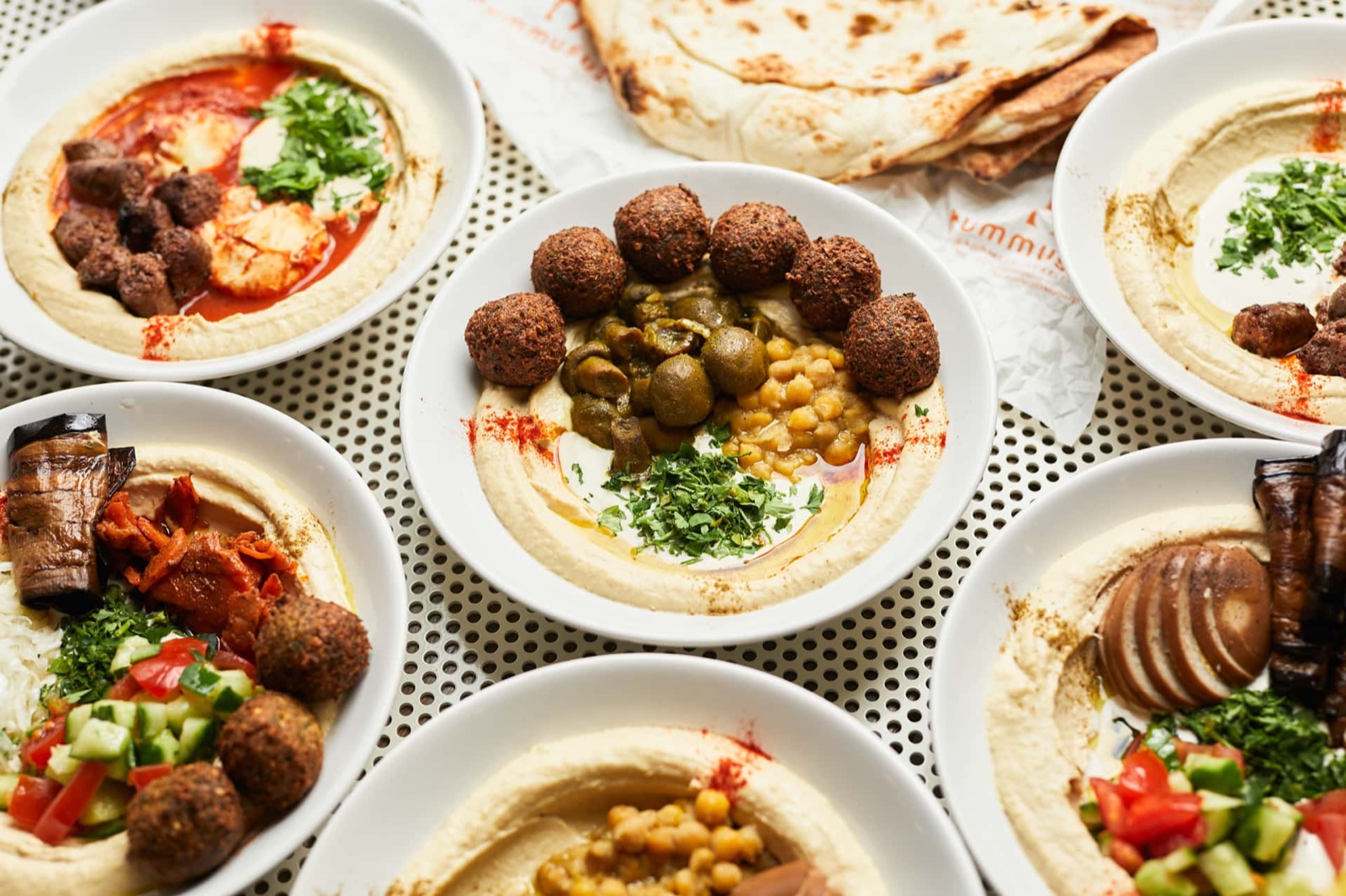 Hummuszos tálak falafellel, pitával és friss zöldségekkel, felülnézetből